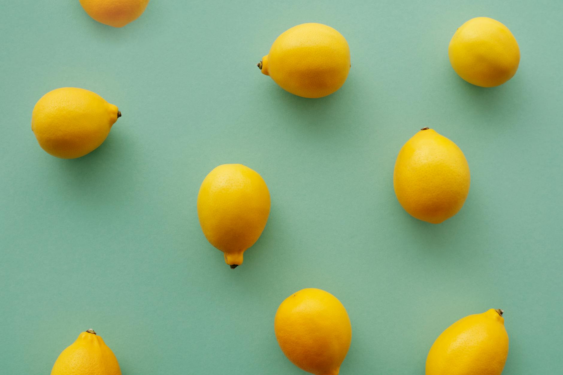 Yellow silicone lemon vibrator surrounded by peeled fruit on a soft yellow background