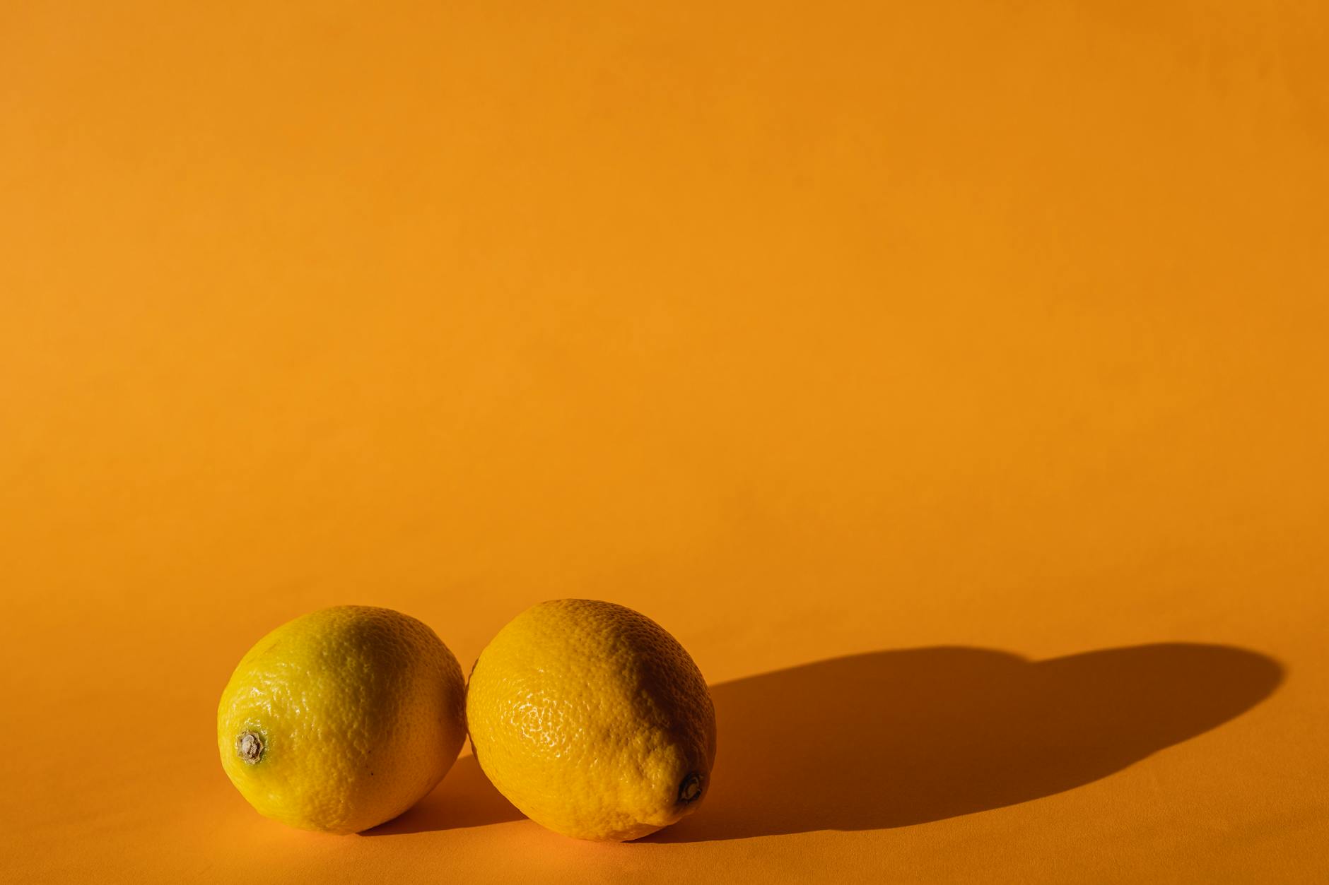 Fresh lemon halves on a pink background symbolizing reconnection and renewed pleasure
